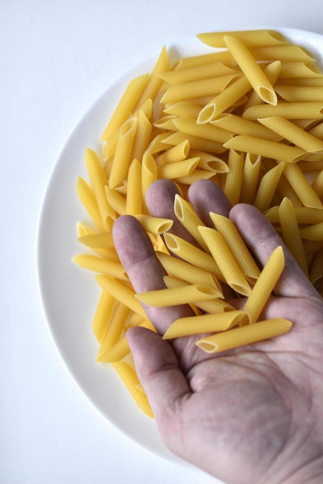 Primer plano de pasta deliciosa amarilla en la mano de un hombre foto