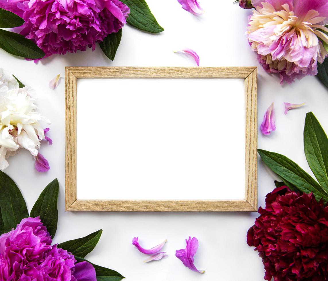 Wooden frame surrounded by beautiful pink peonies on a white background photo