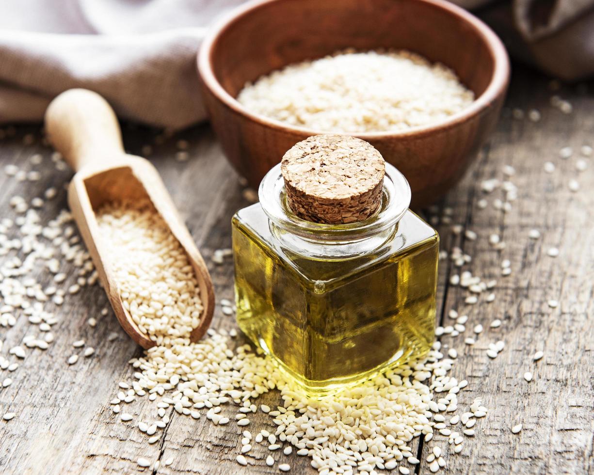 Sesame oil and seeds on a rustic table. photo