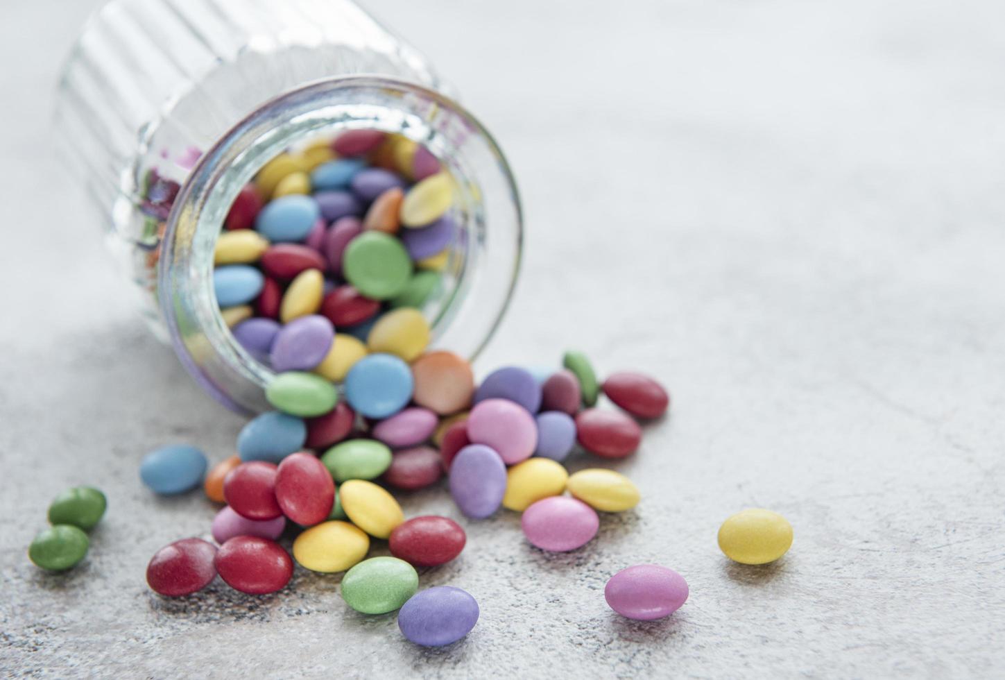 Jar with multicolored dragee candies photo
