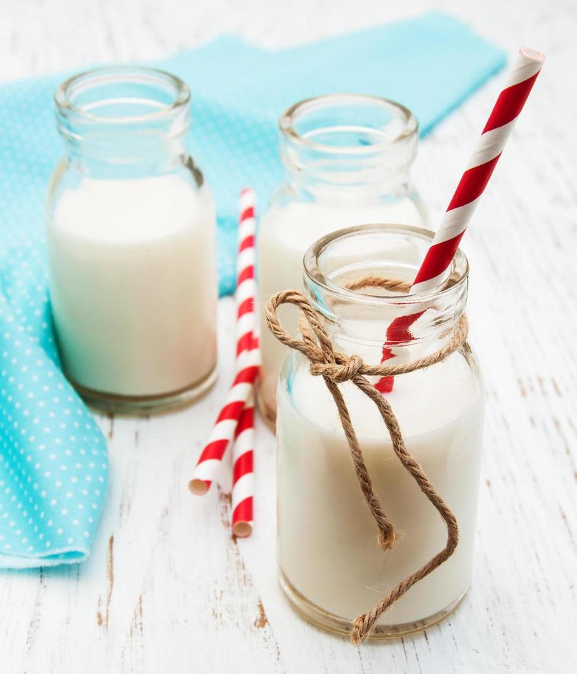 Bottles of milk with straws on a wooden background photo