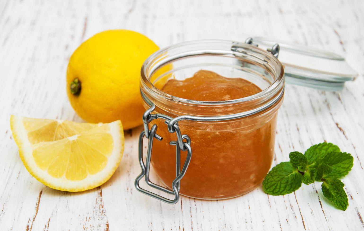 Lemon jam and fresh lemons on a wooden background photo