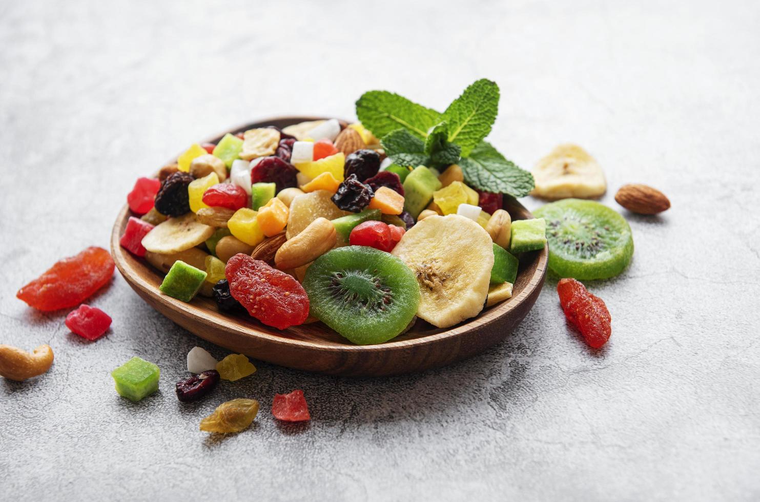 Bowl with various dried fruits and nuts on a gray concrete background photo