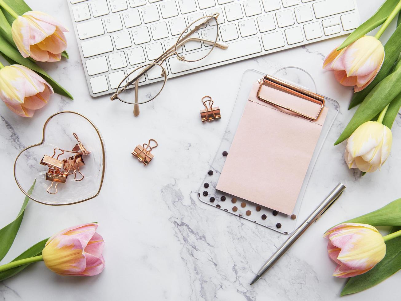 Freelancer or blogger workplace with keyboard, notepad, and tulips photo