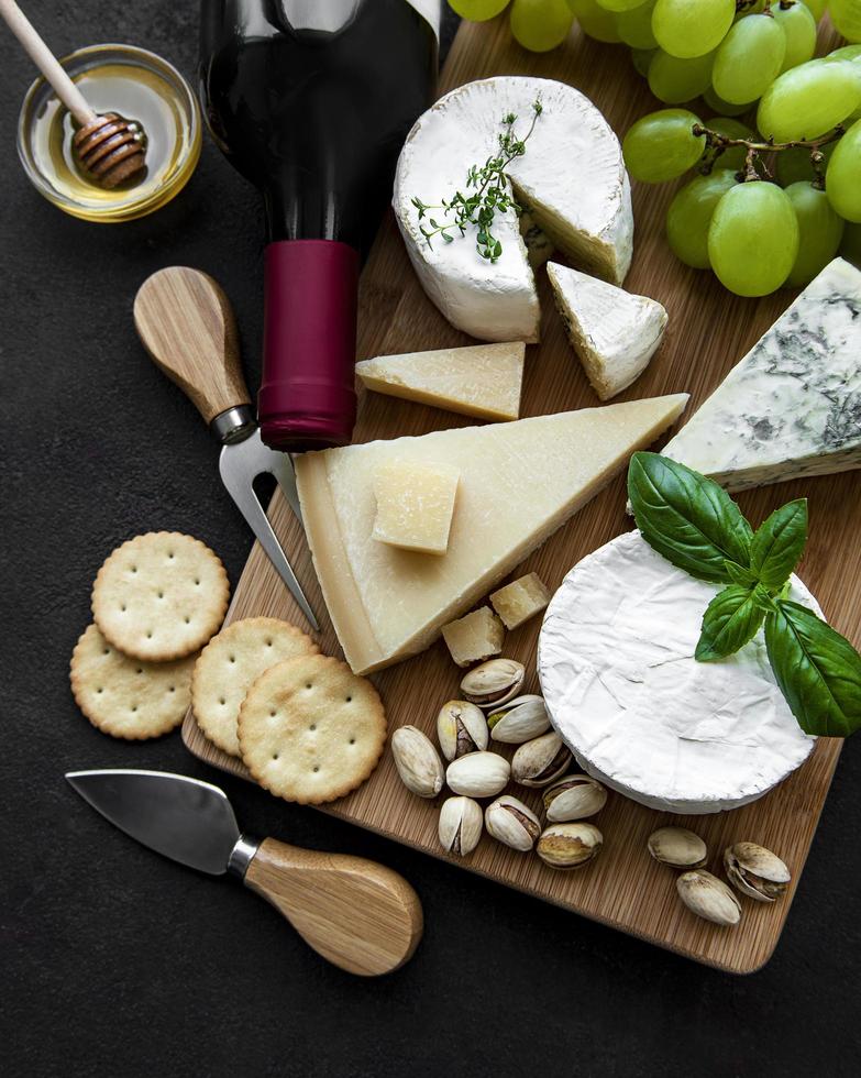 Varios tipos de queso, uvas y vino en una mesa de madera foto