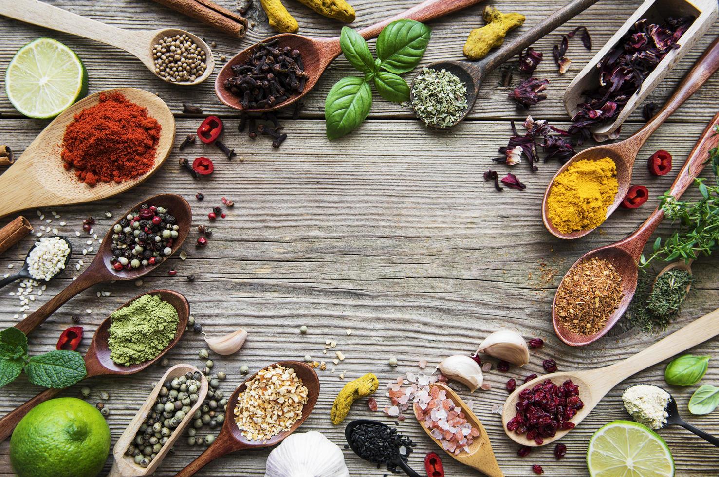 A selection of various colorful spices on a wooden table in spoons photo