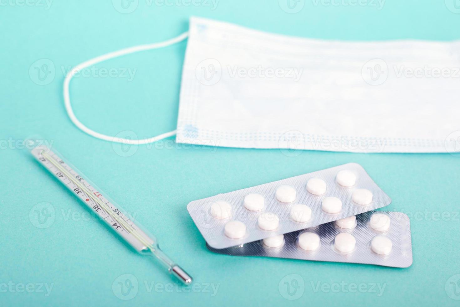 Antiviral medical products- pills, thermometer, mask on a blue background photo