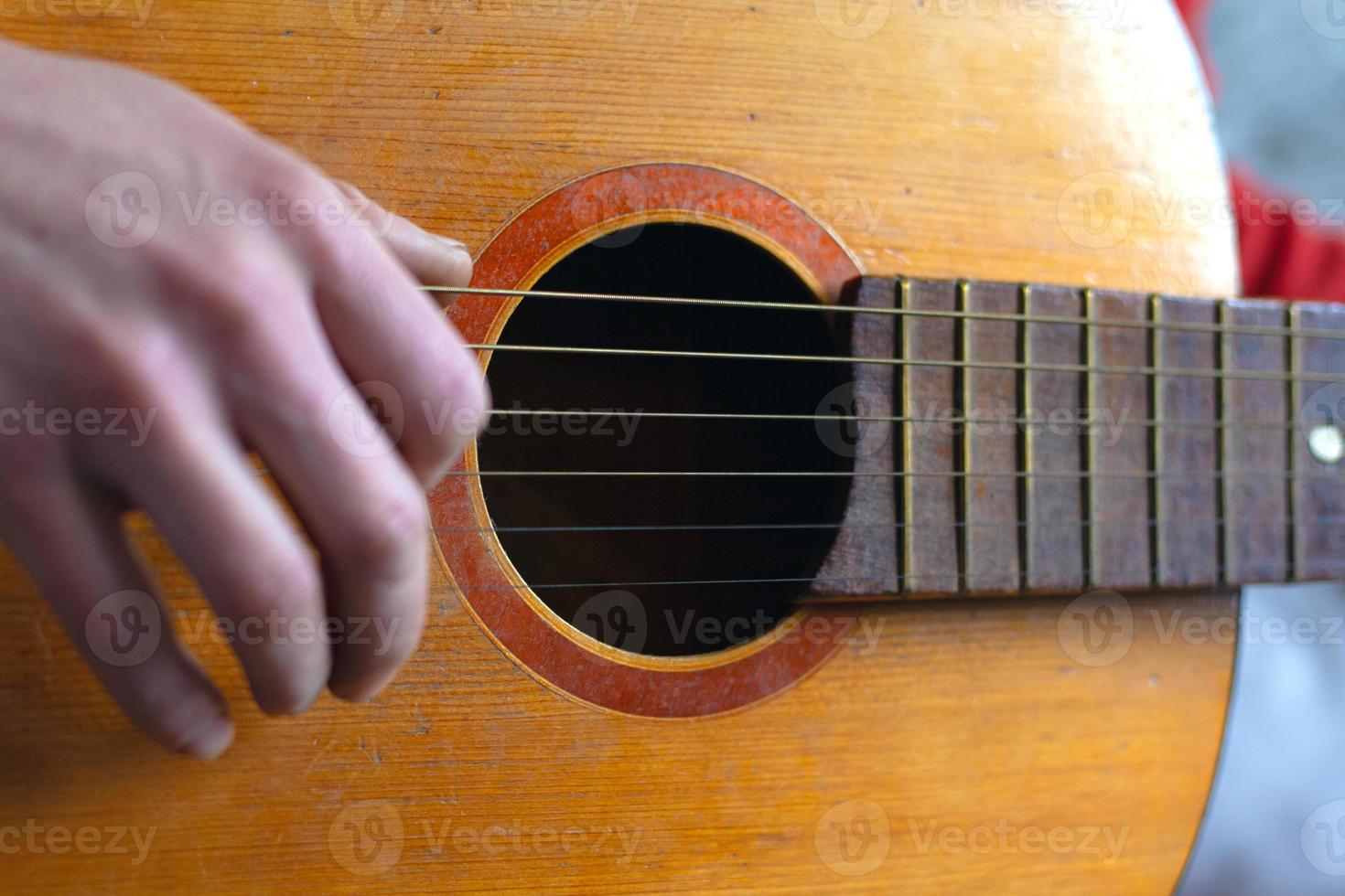 Fingers play the strings on a classic acoustic guitar photo