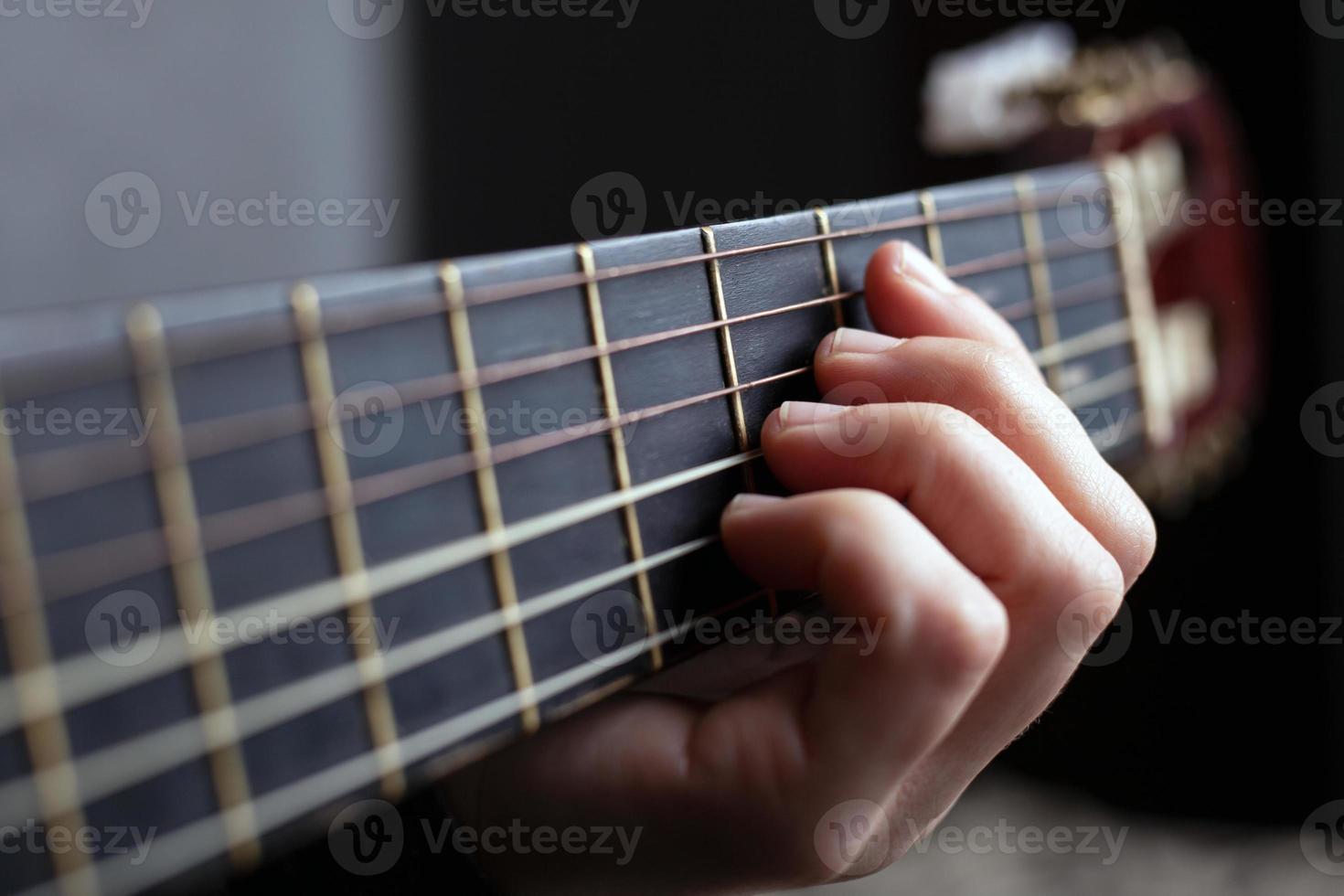 manos femeninas en el cuello de una guitarra acústica, tocando la guitarra foto