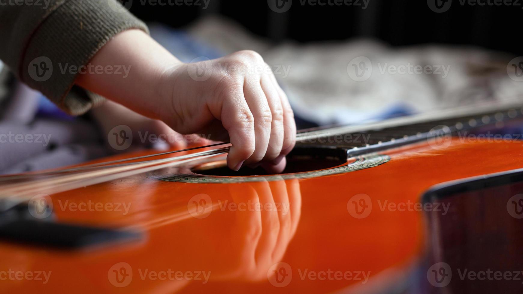 Little girl tries to tear the strings on the guitar photo
