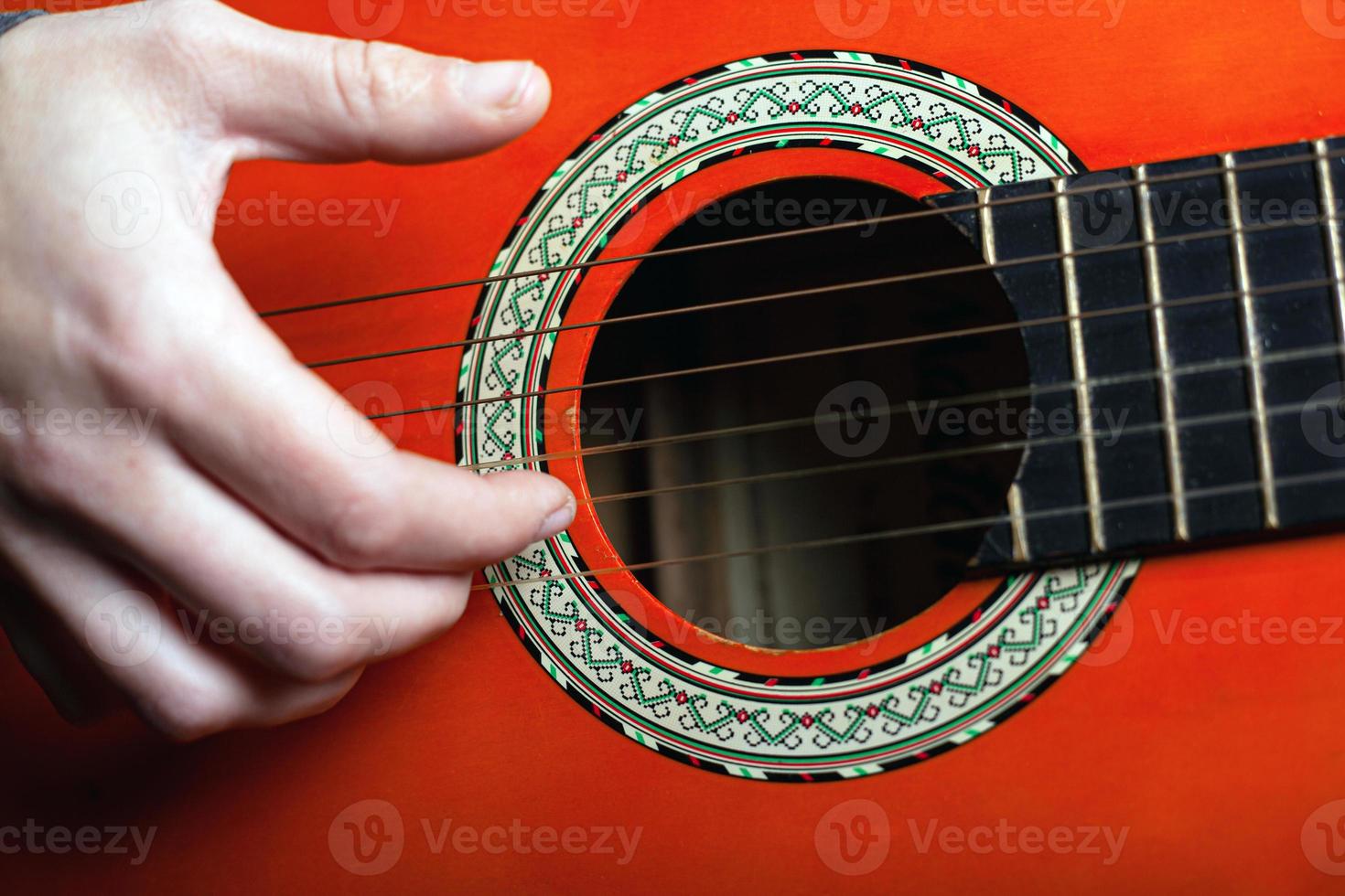Fingers play the strings on a classic acoustic guitar photo
