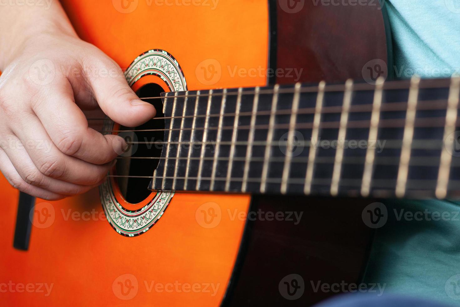 Male hand plays acoustic guitar strings photo