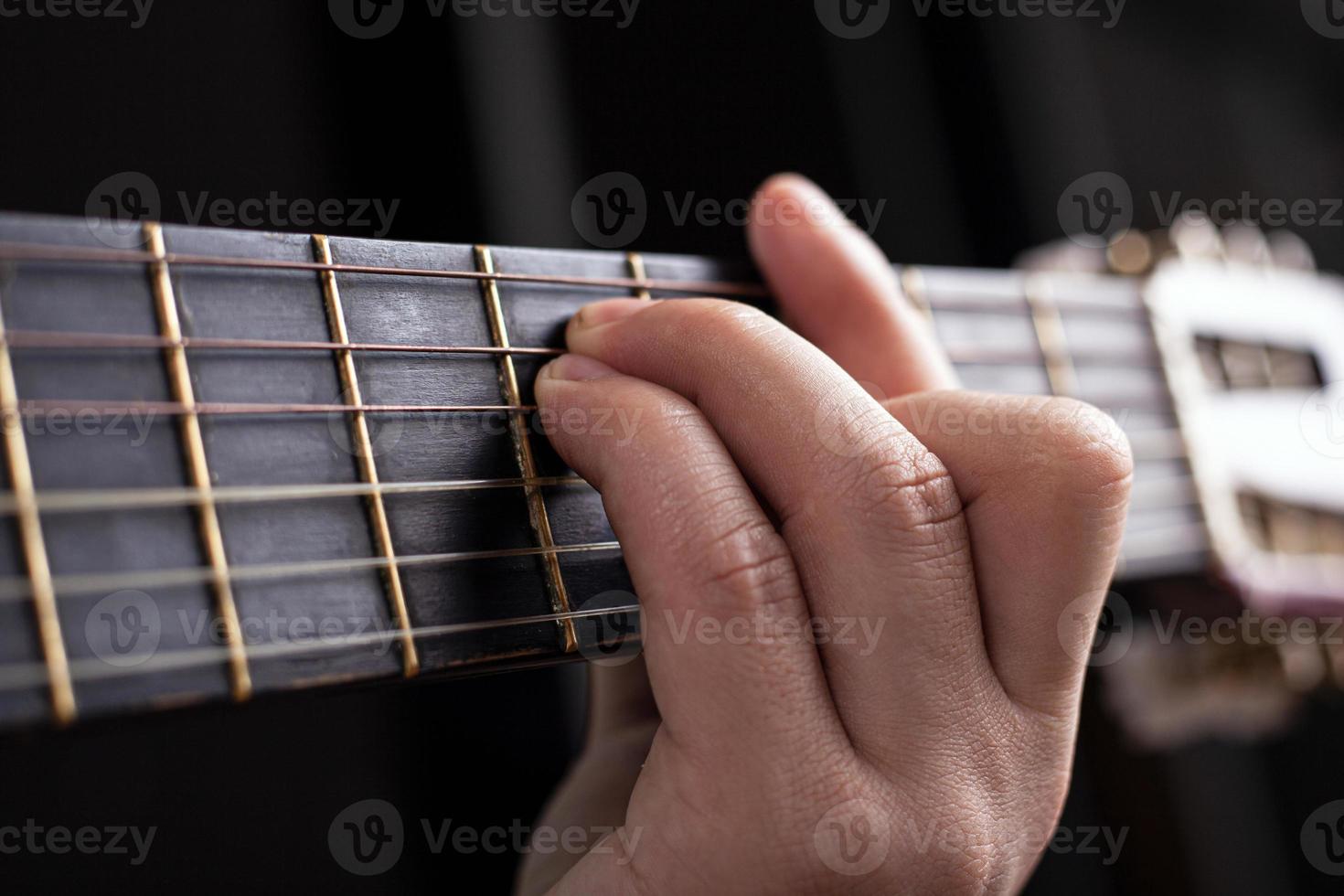 Male hand clamps an acoustic guitar chord photo