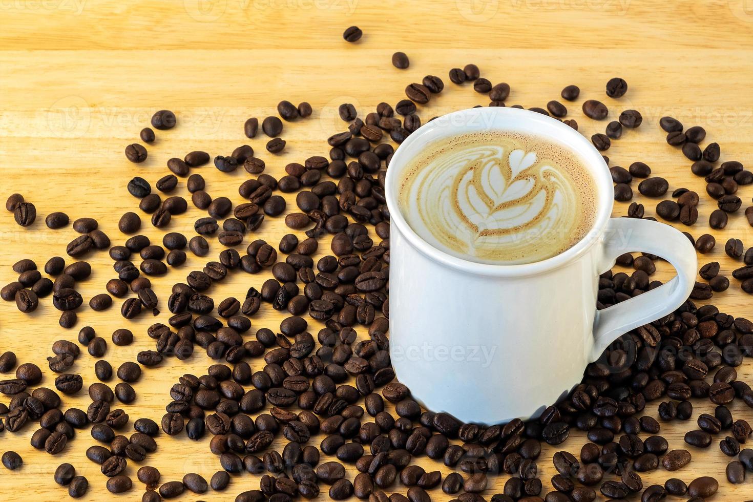 Top view of a mug of coffee with beans on wooden background. photo
