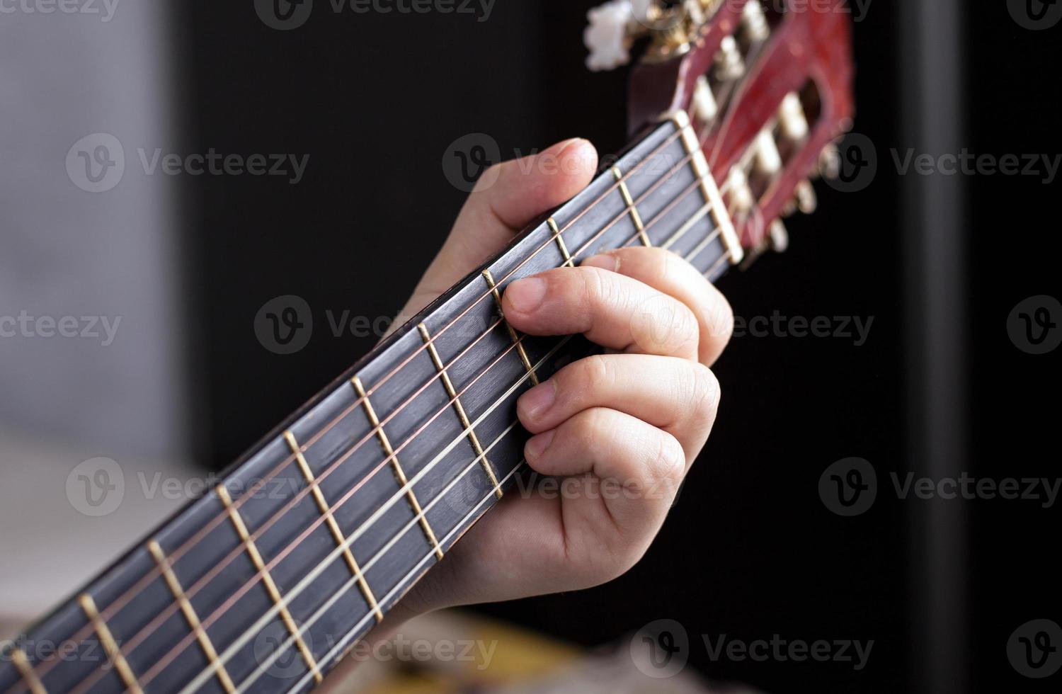 La mano del guitarrista aprieta los dedos sobre los acordes de una guitarra acústica. foto