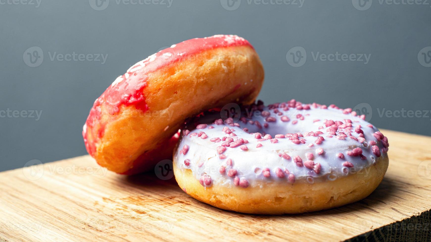 Sweet glazed donuts on wooden board photo