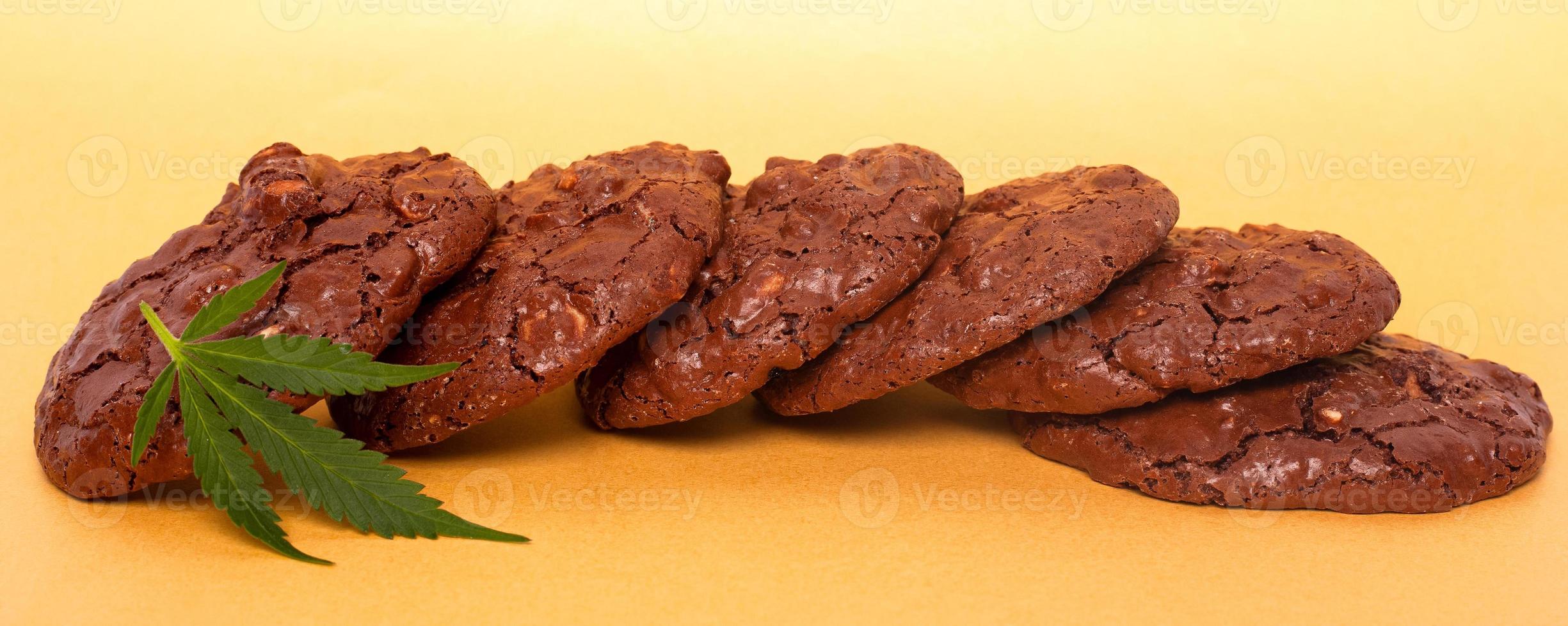 Oatmeal cookies and green leaf of cannabis on a yellow background photo