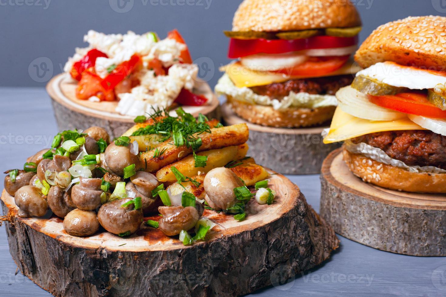 patatas fritas con champiñones y jugosas hamburguesas de carne en tocones de madera foto