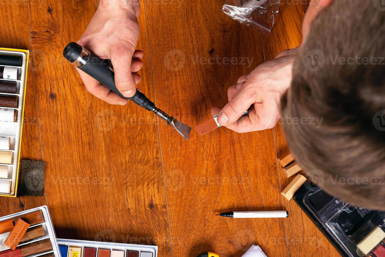 Sealing chips and scratches on the laminate, the master fix a defect on a floor with wax and a soldering iron photo