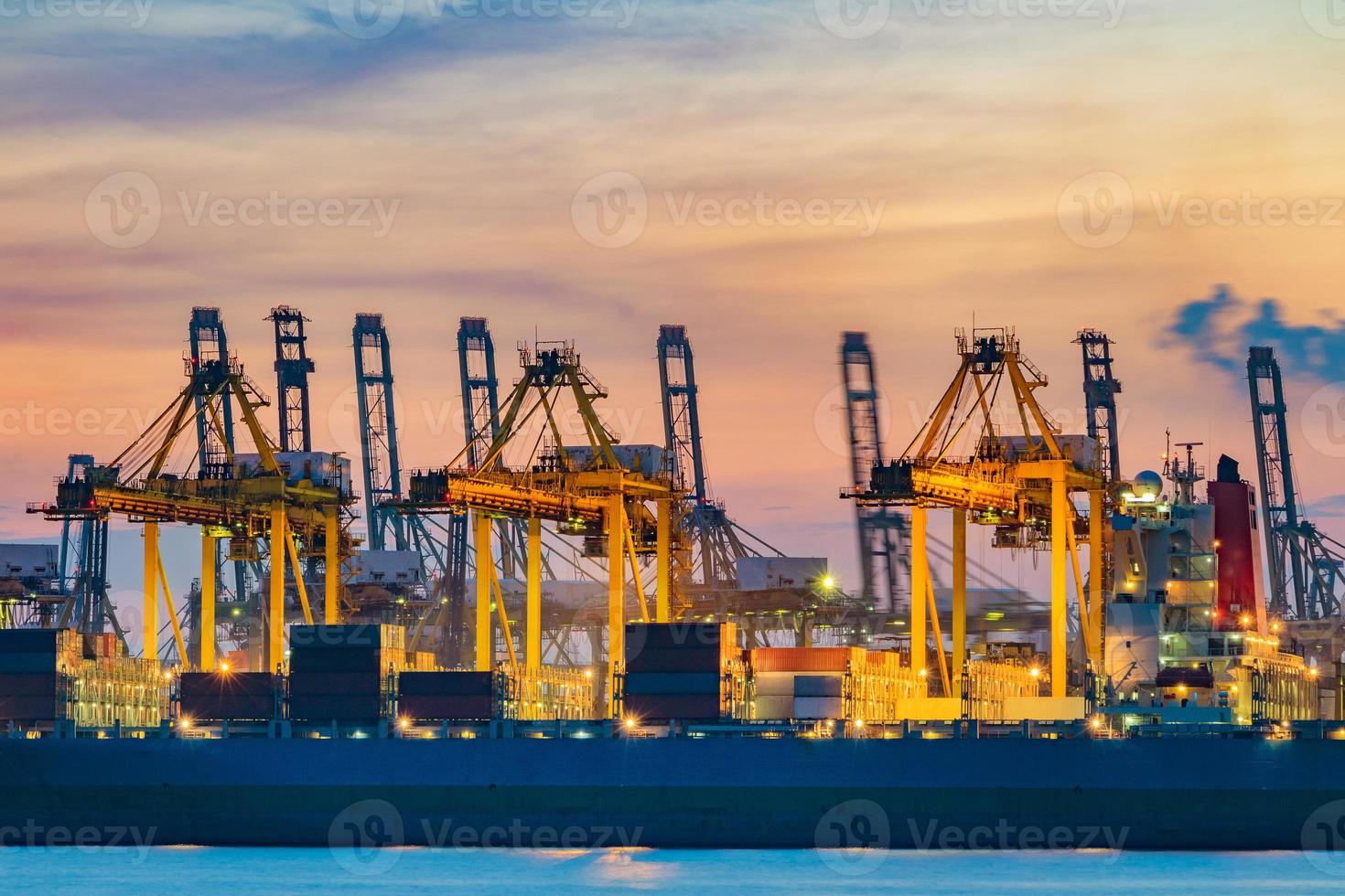 Freighter ship loading cargo at loading dock on twilight time in Singapore photo