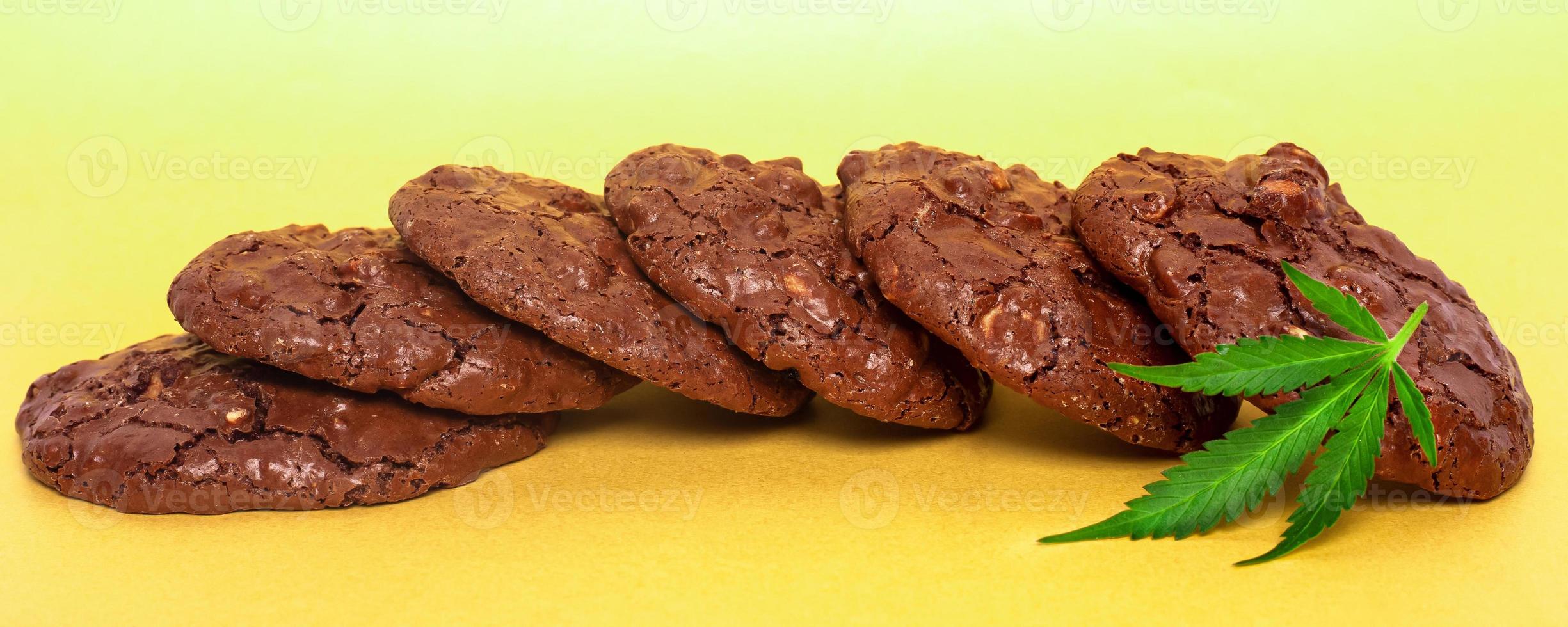 Oatmeal cookies and green cannabis leaf on a yellow background photo