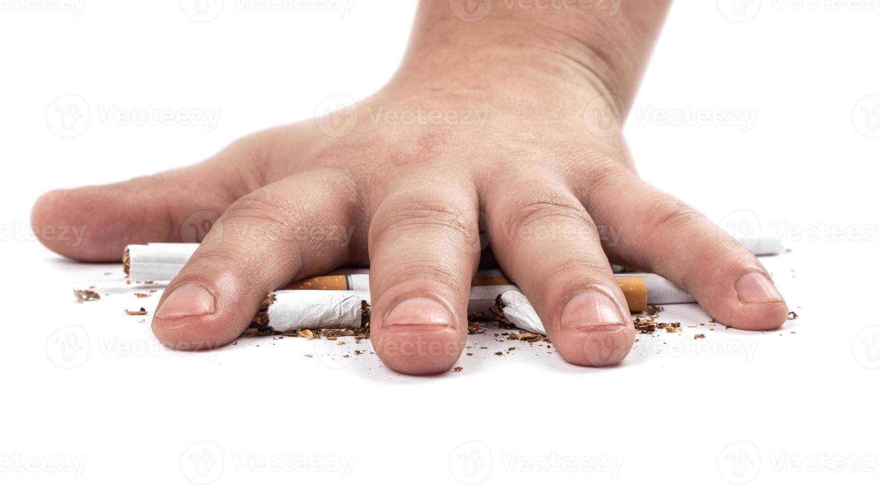 Fumador aplasta un cigarrillo con la mano sobre fondo blanco. foto