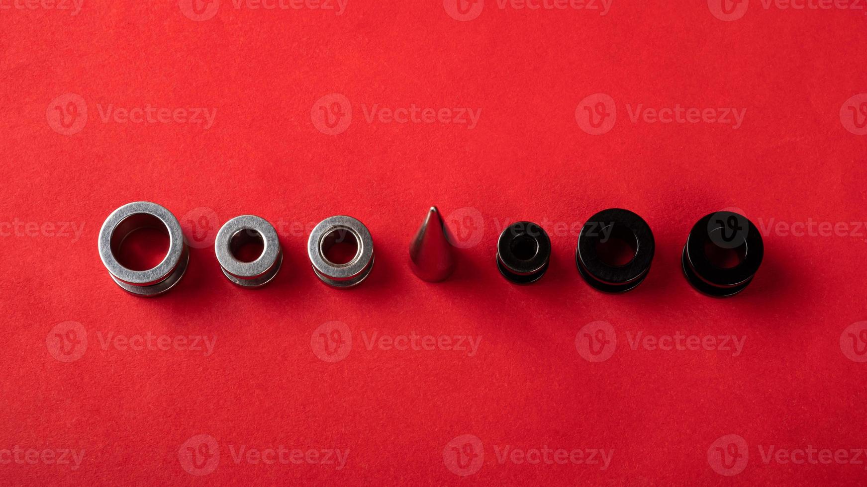Ear piercing jewelry on a red background photo