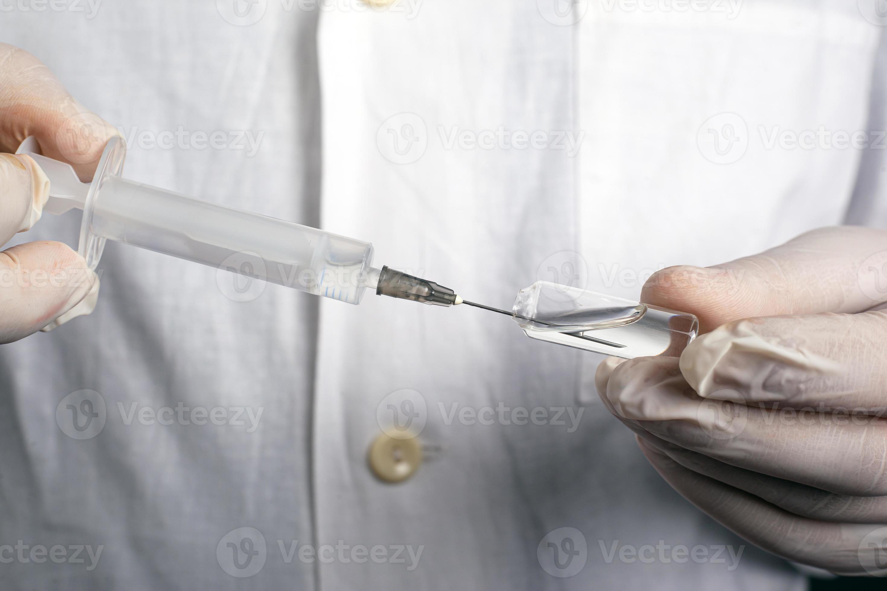El médico saca el medicamento con una jeringa de la ampolla. foto