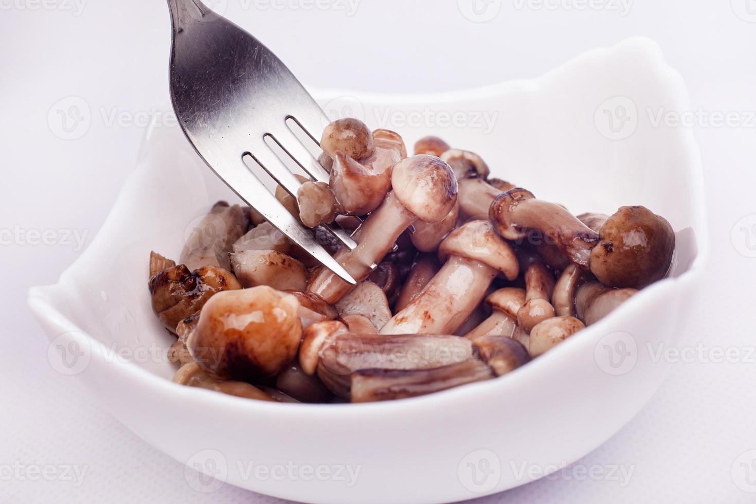 Small pickled mushrooms impaled on fork on white background photo