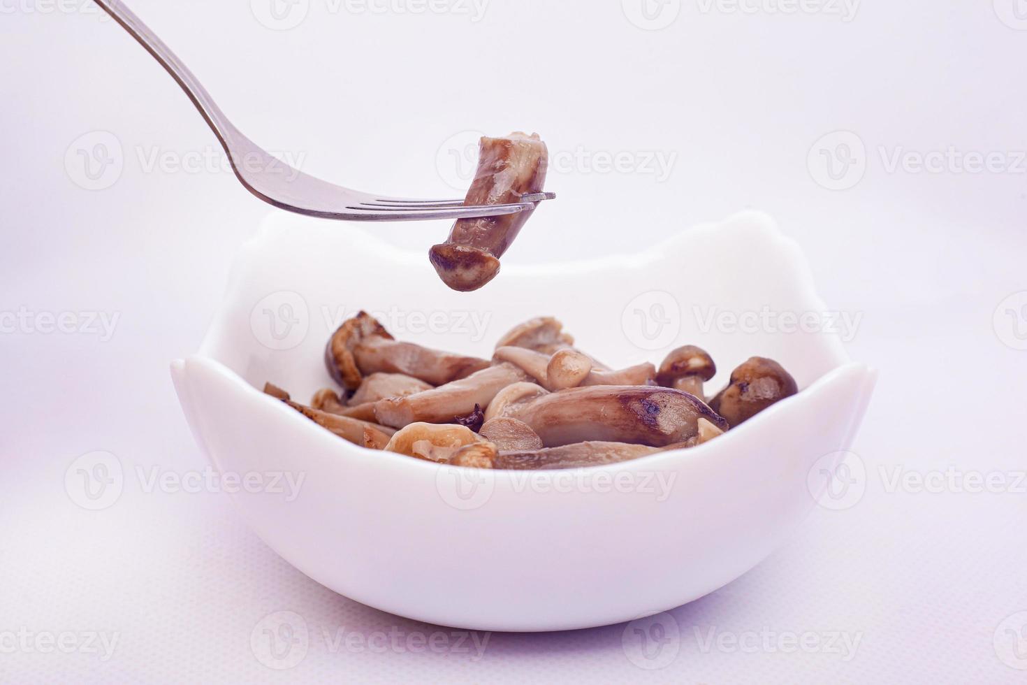 Small pickled mushrooms impaled on fork on white background photo