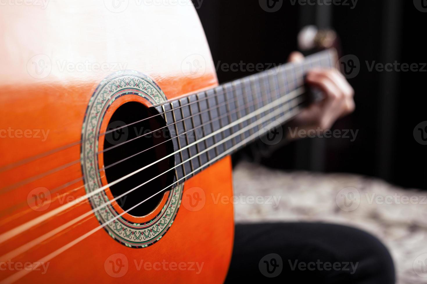 tocando la guitarra acústica clásica española en color naranja foto