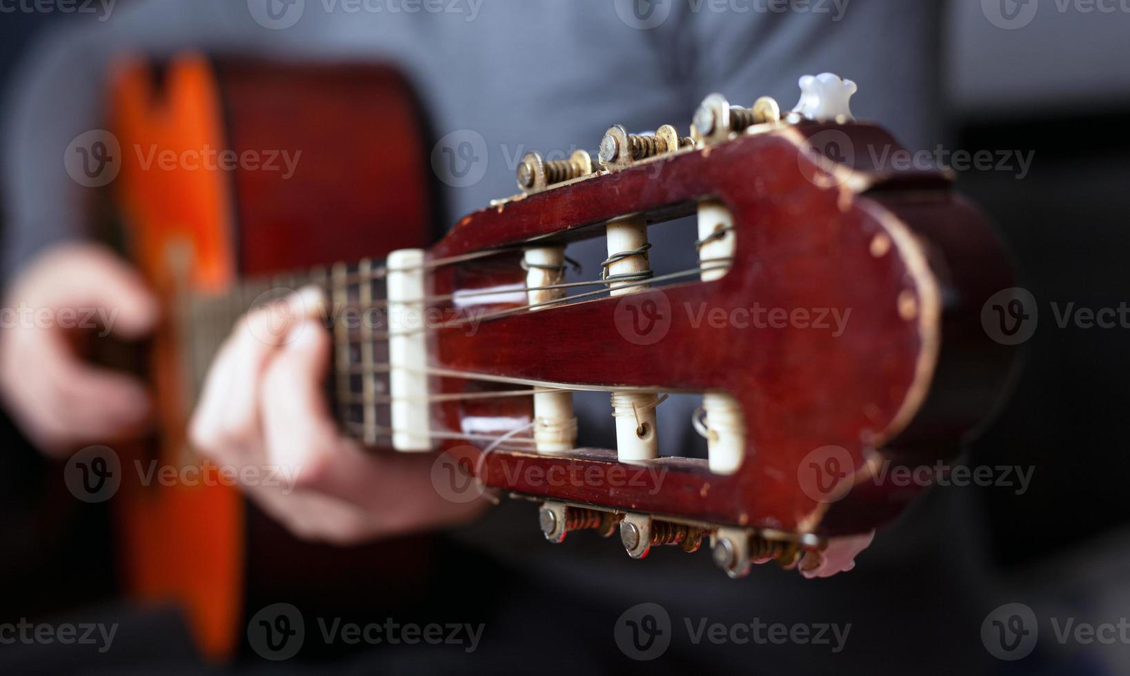La mano del guitarrista aprieta los dedos sobre los acordes de una guitarra acústica. foto