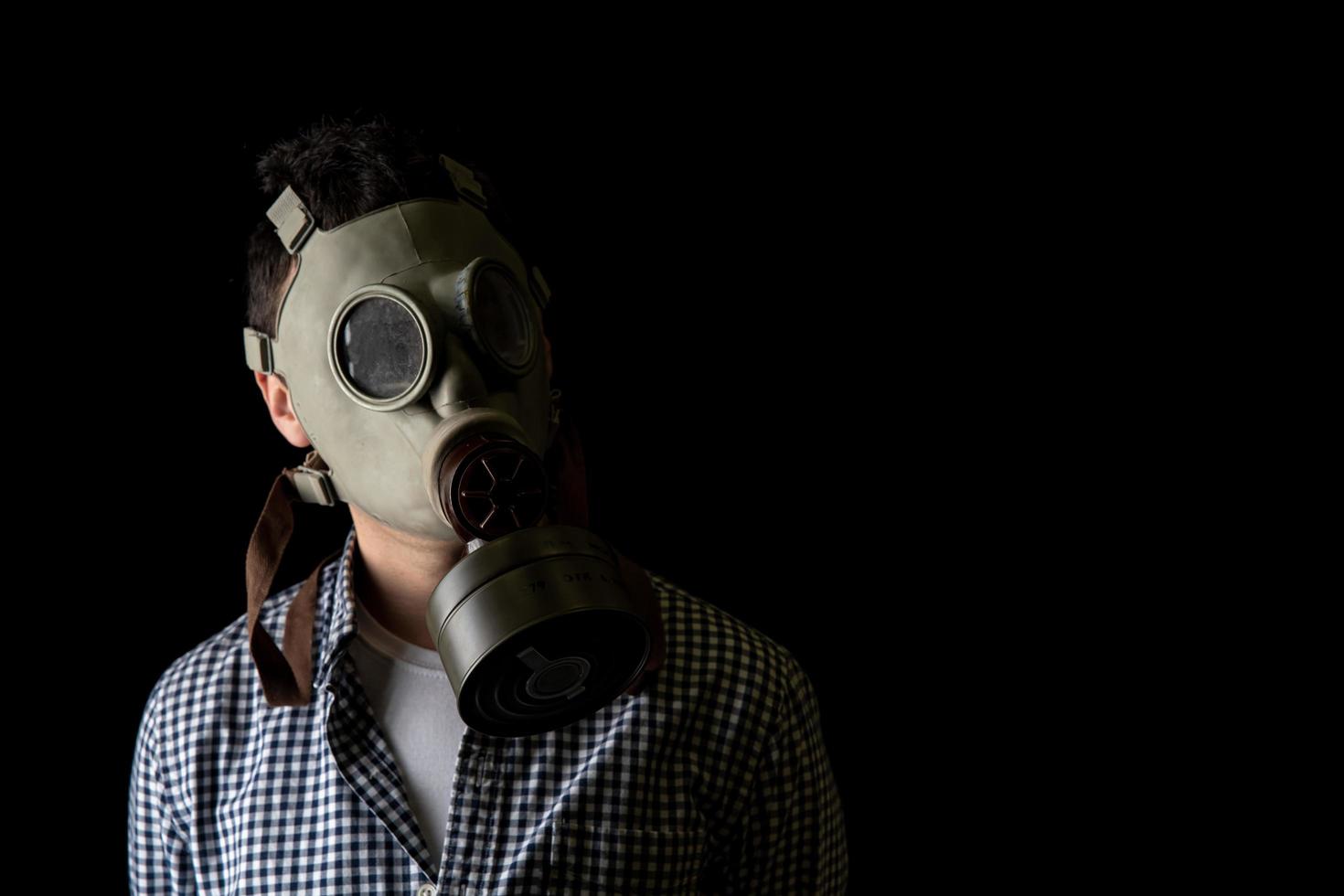 Hombre con una máscara de gas sobre un fondo negro, protección contra virus foto