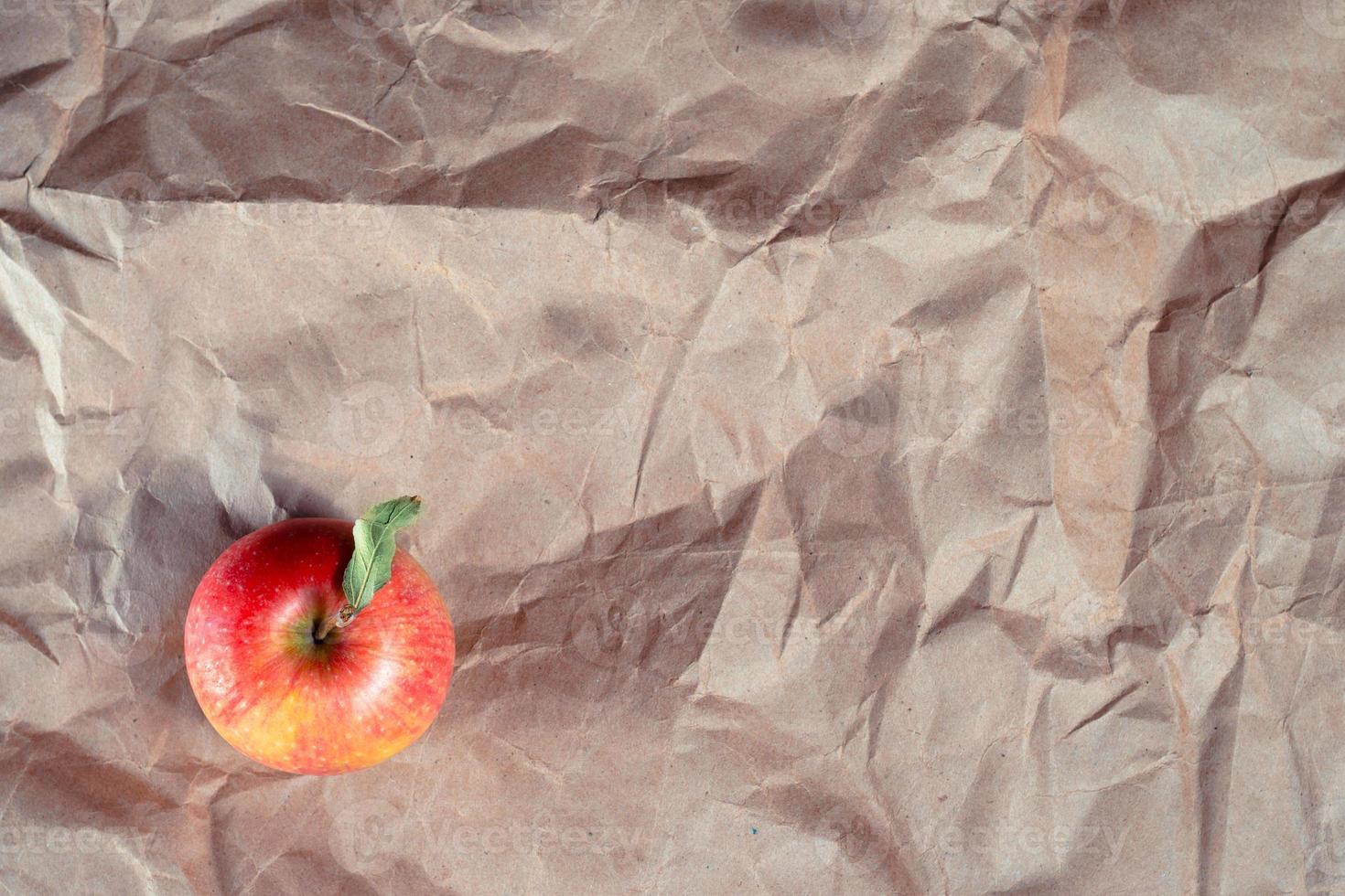Red apple on crumbled craft paper photo