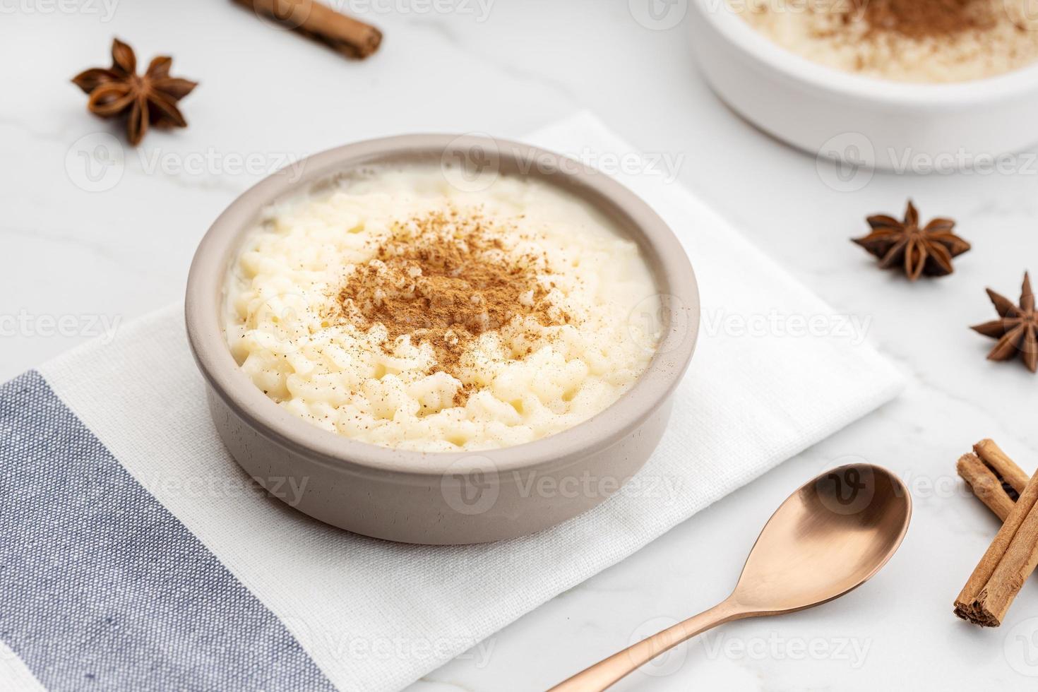 Creamy rice pudding with cinnamon in bowl on white marble table photo