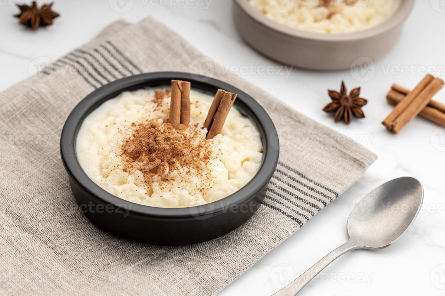 Creamy rice pudding with cinnamon in bowl on white marble table photo