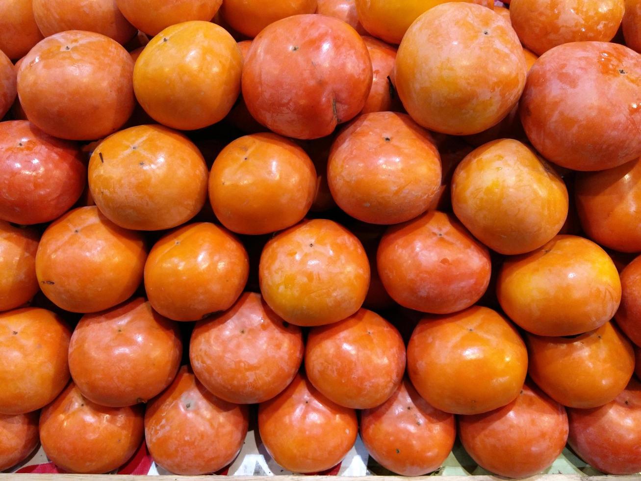 Frutas orgánicas de caqui en pila en el mercado local de agricultores. foto