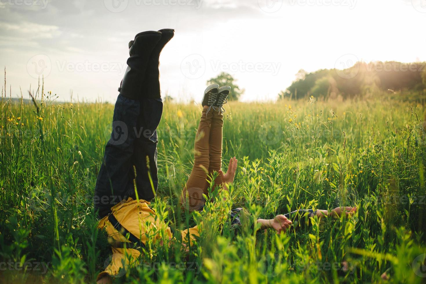 niño con niña en un campo acostado sobre la hierba verde con las piernas y las manos en alto. foto