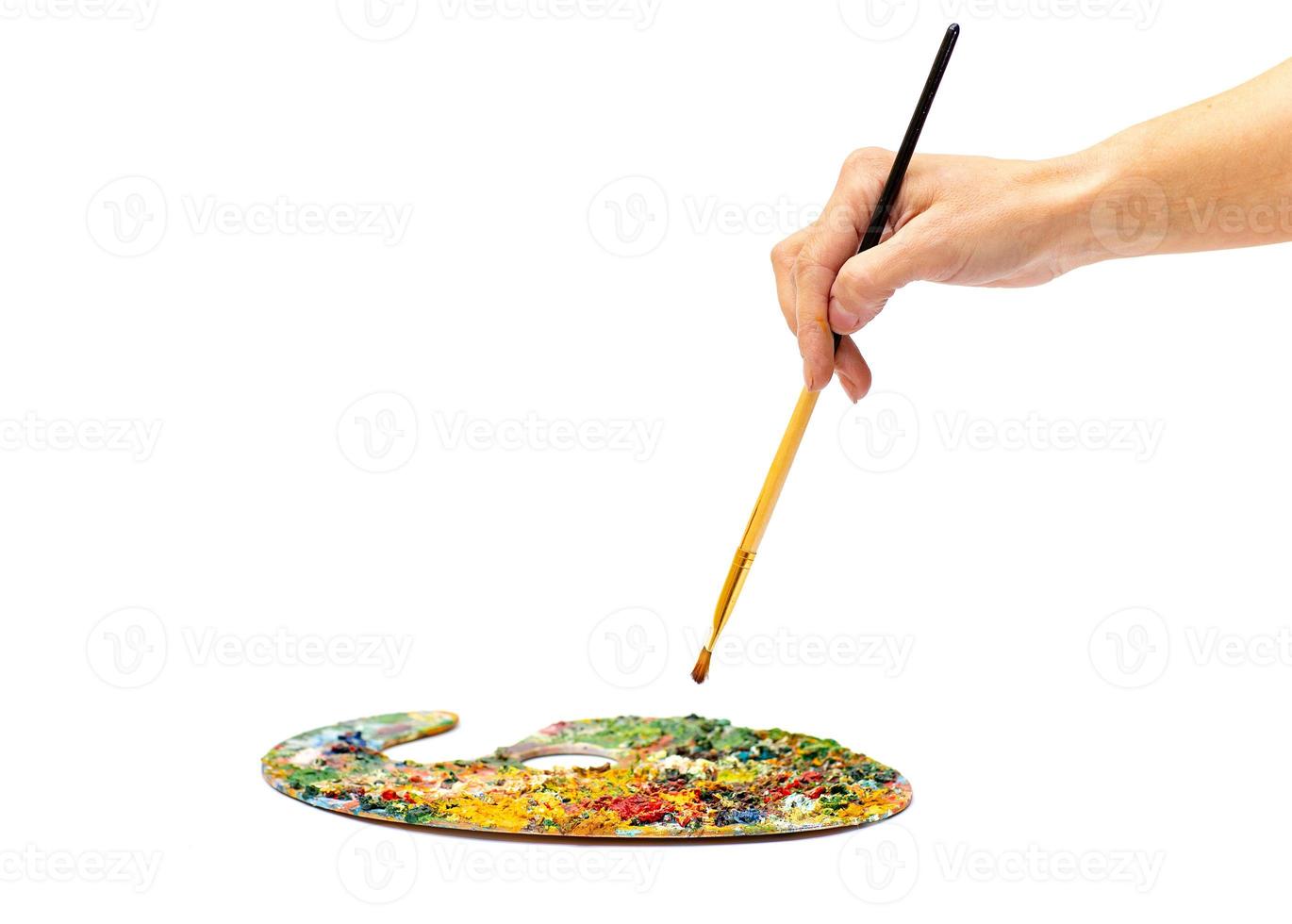 Young woman holding a brush with color paint on white background, closeup. Painter paints a brush on a white background. photo