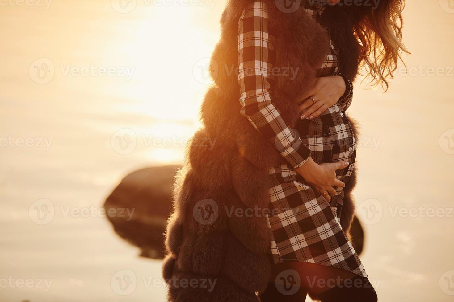 Pregnant woman in a beautiful dress. Focus on the abdomen. photo