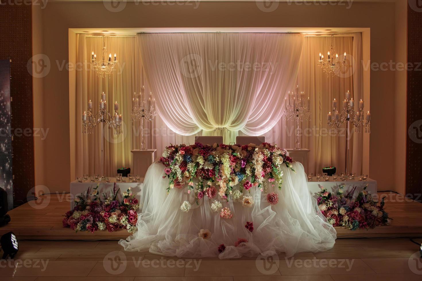 mesa festiva decorada con una composición de flores blancas, rojas y rosadas y vegetación en el salón de banquetes foto