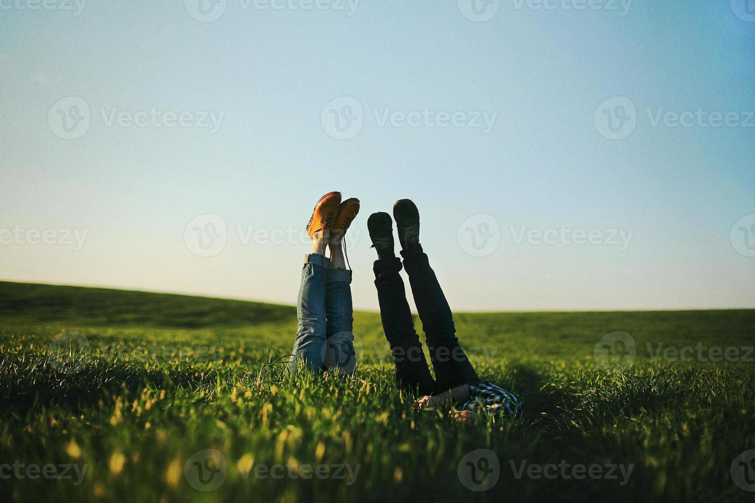View of a man and woman's legs sticking up out of tall green grass on a summer day. Selective focus. photo