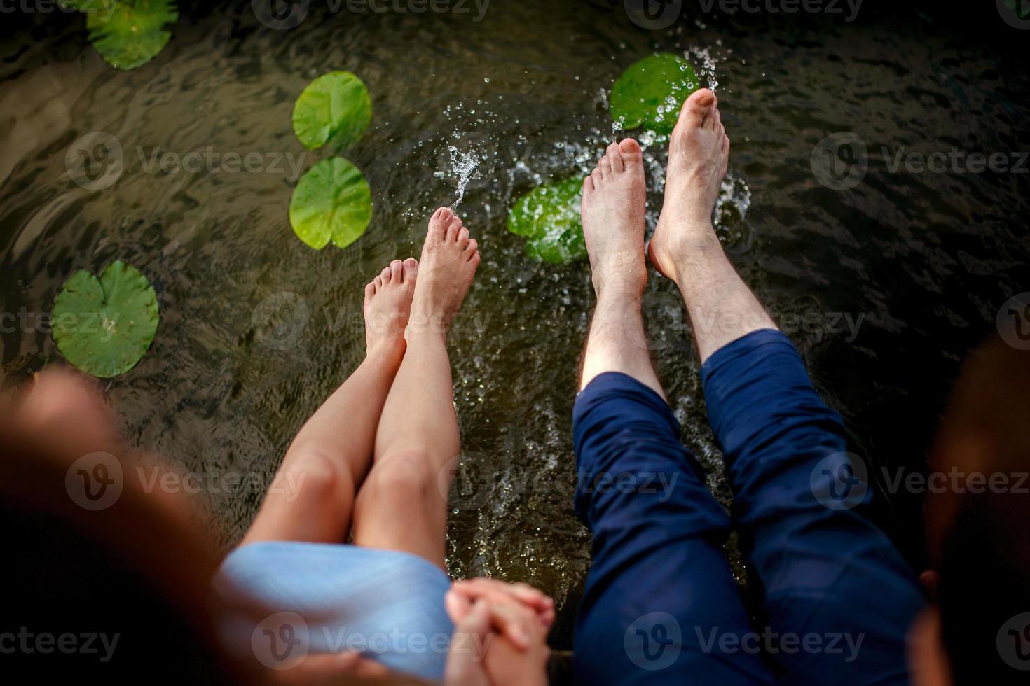 pareja chapoteando sus pies en el agua al atardecer foto