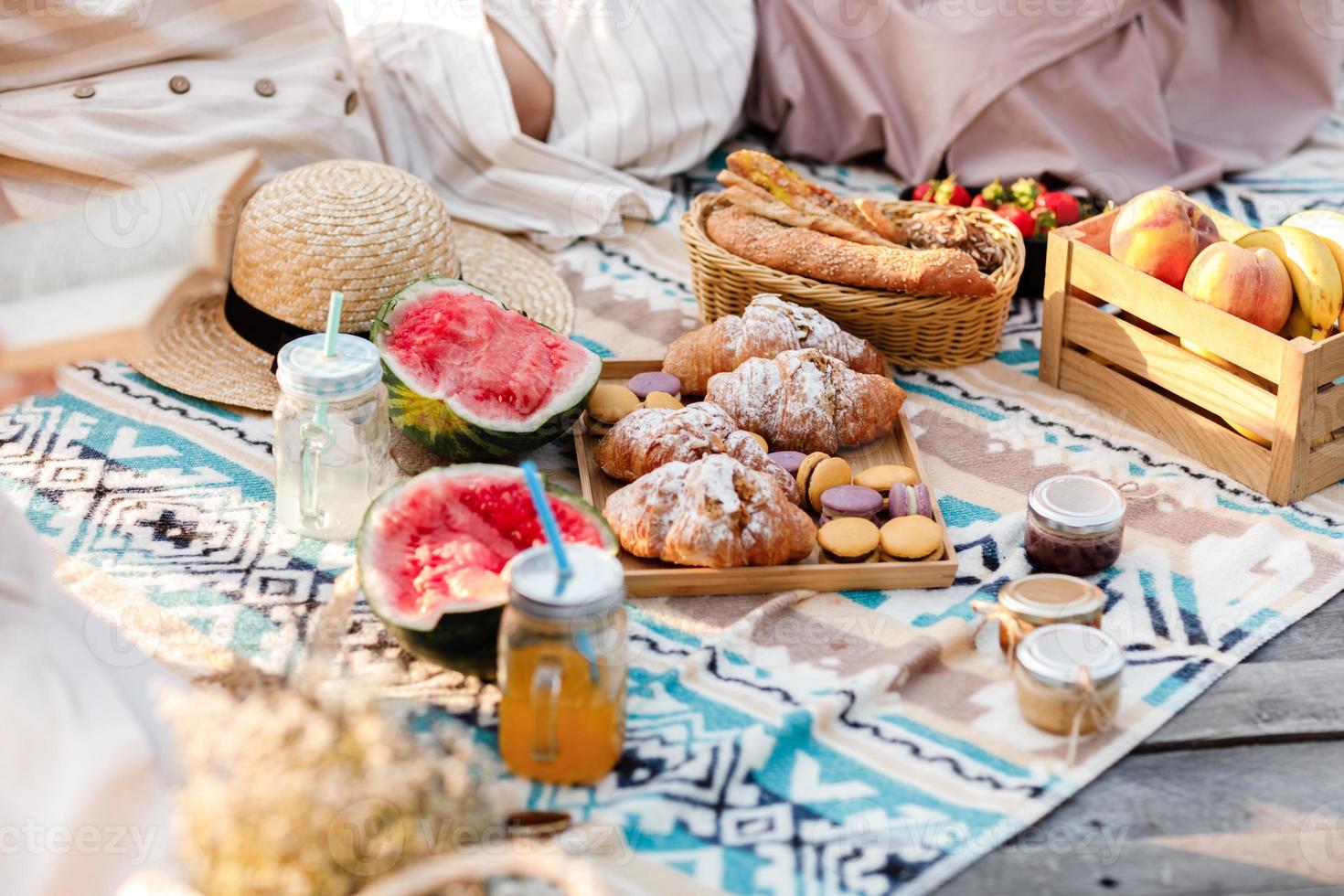 Picnic at the park. Fresh fruits, ice-cold sparkling drinks, and croissants on a hot summer day. Picnic lunch. Selective focus. photo