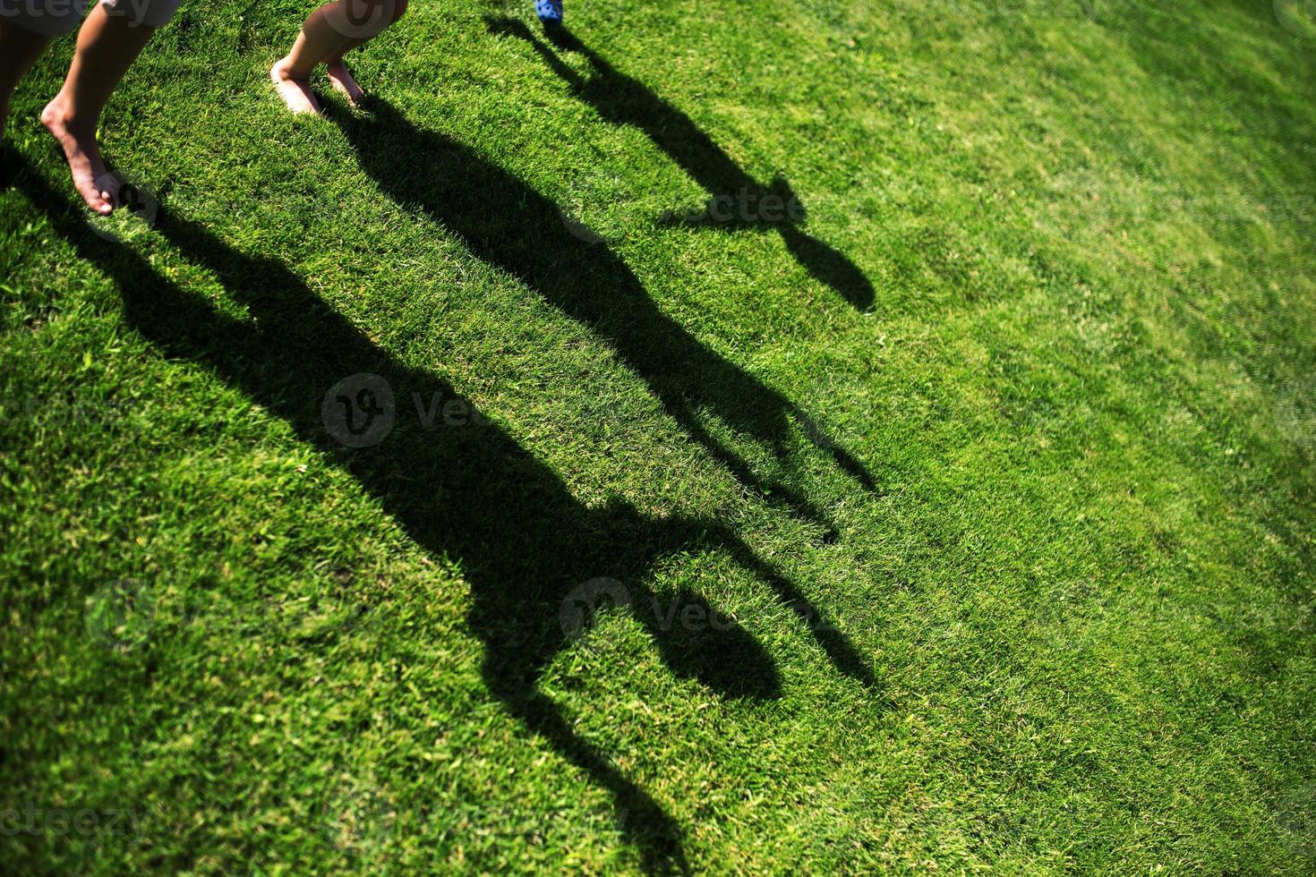 Silueta de tres personas de pie con las manos estiradas sobre la hierba verde foto