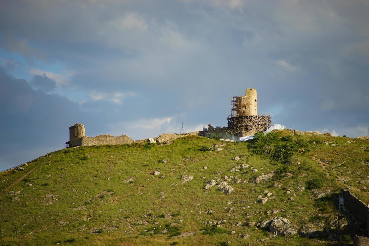 Vista de la fortaleza genovesa en la ladera de una montaña con un nublado cielo azul en Crimea foto