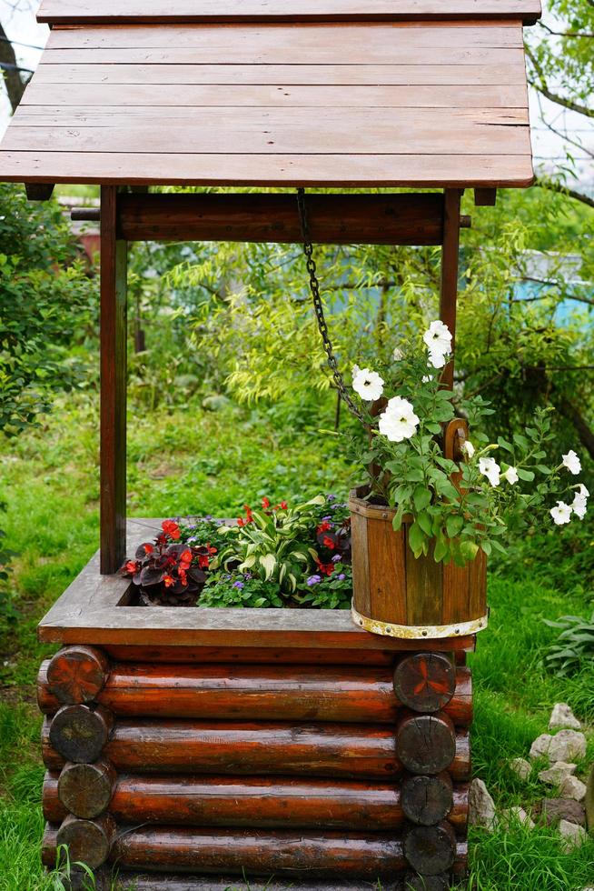 Wooden water well decorated with flowers in pots photo