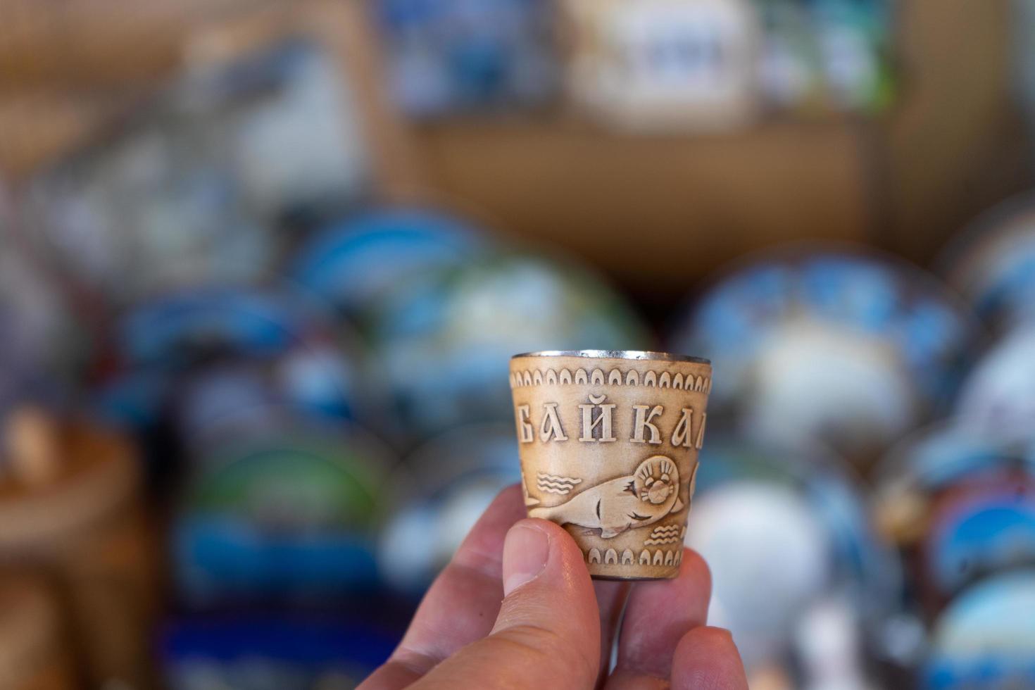 Hand holding a shot glass with the image of a seal on birch bark photo