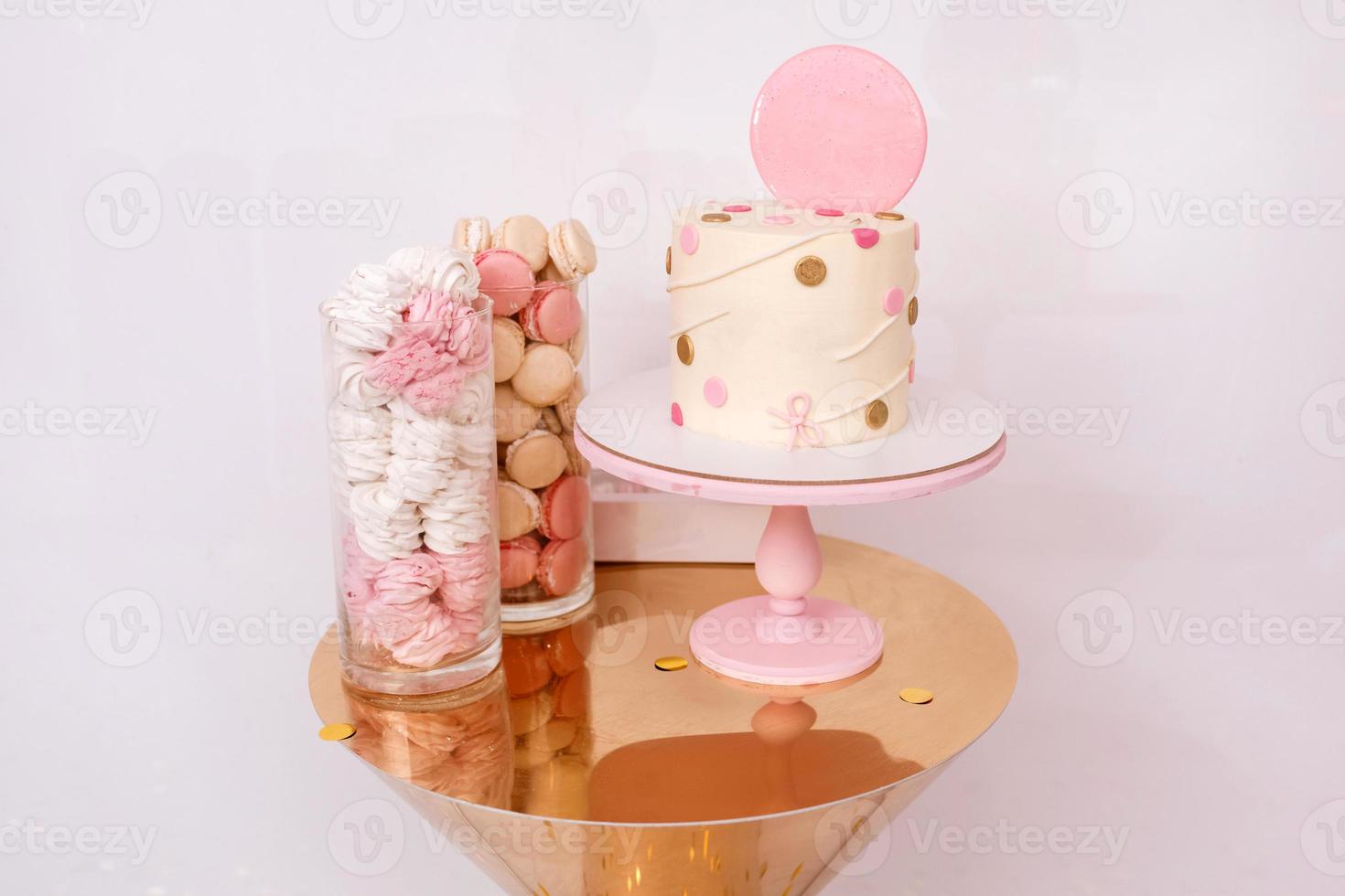 Beautiful birthday cake with pink decor for the birthday of a child. Candy bar with macaroons and marshmallows. photo