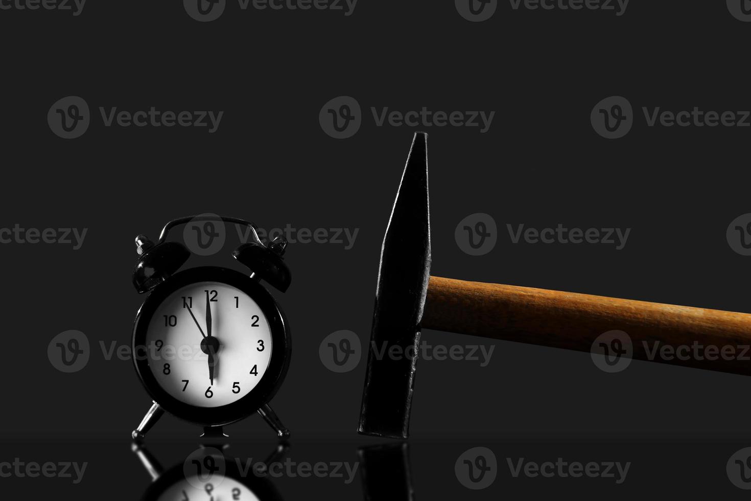 Black old-style alarm clock isolated. Wake up with a hammer on a black background photo